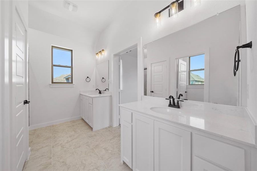 Spacious bathroom featuring dual white vanities with integrated sinks and white countertops