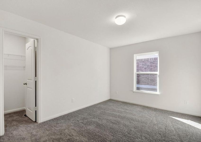 Secondary bedroom with a walk-in closet and a window.