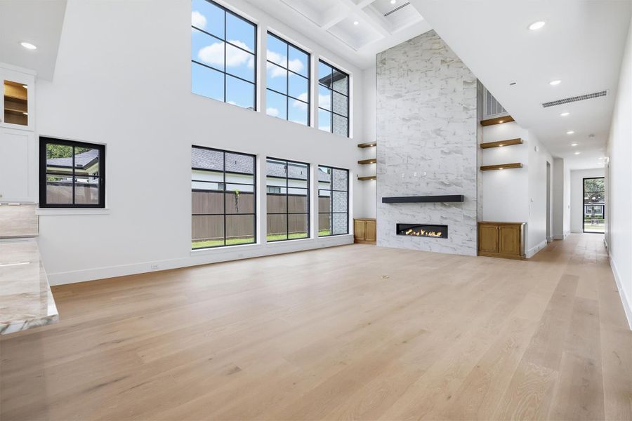 The great room features custom lighting, a gas fireplace, and paneled ceilings.
