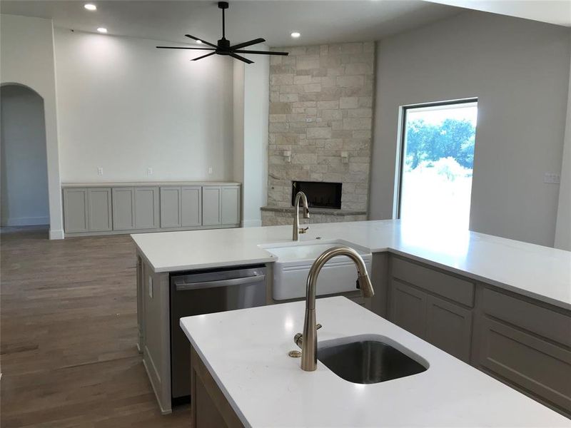 Kitchen with ceiling fan, dark wood finished floors, open floor plan, arched walkways, and stainless steel dishwasher