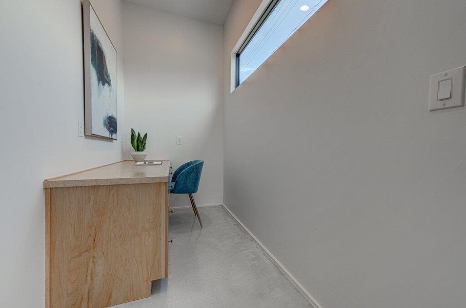 Office with built in desk, baseboards, and concrete flooring