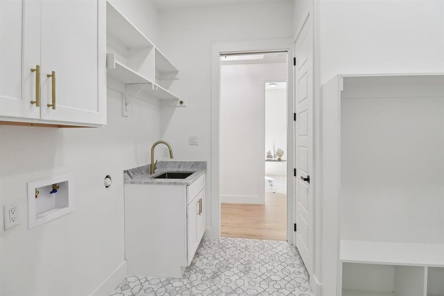 Washroom featuring cabinet space, hookup for a washing machine, light tile patterned floors, and wet bar