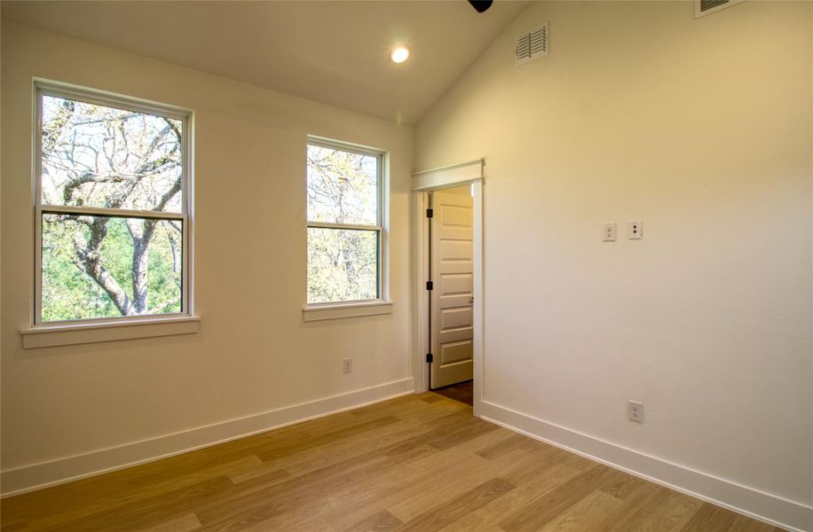 Primary bedroom featuring light wood-style floors, high vaulted ceiling, and recessed lighting Primary bedroom featuring light wood-style floors, high vaulted ceiling, and recessed lighting