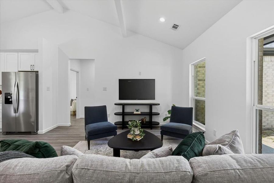 Vaulted ceiling with exposed beams, LVP flooring, white walls, recessed lighting, and large windows