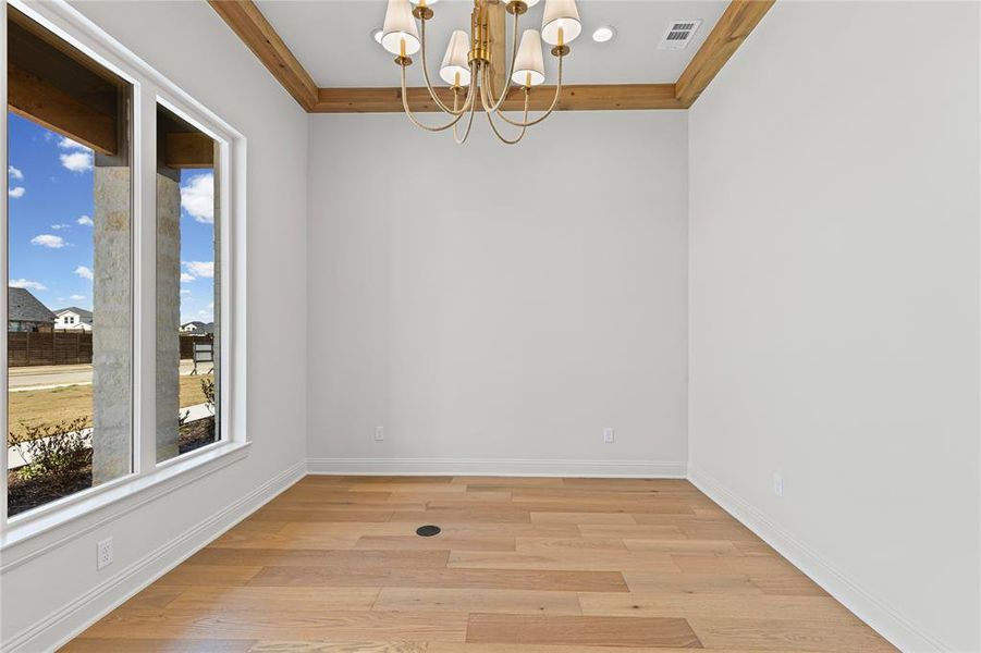 Empty room with hanging lights, light wood finished floors, and ornamental molding