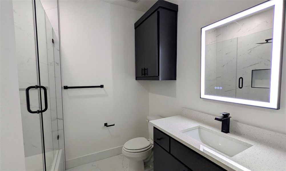 Bathroom featuring baseboards, vanity, toilet, marble finish floor, and a marble finish shower