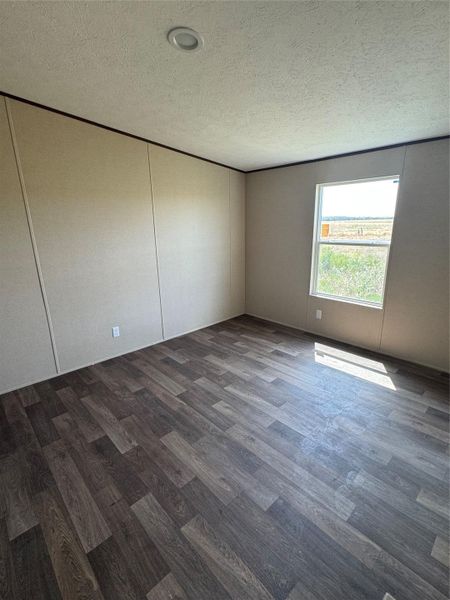 Natural light streams across wood-look flooring from a window showcasing scenic open views.