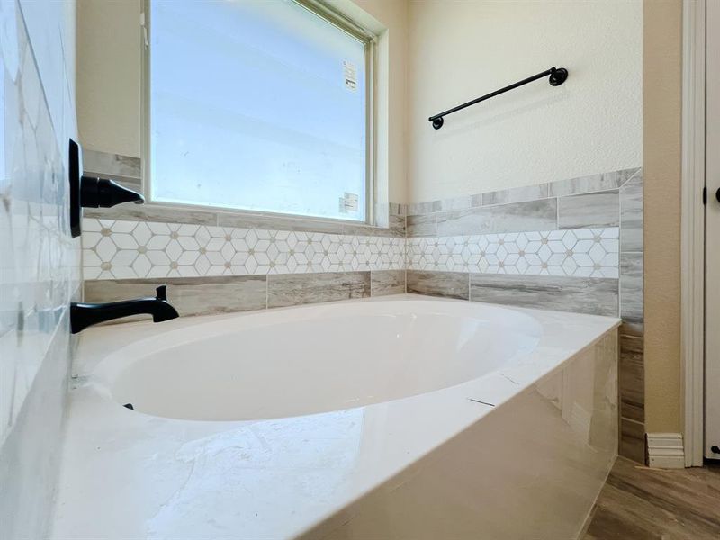 Full bath featuring a bath and dark wood finished floors Full bath featuring a bath and dark wood finished floors