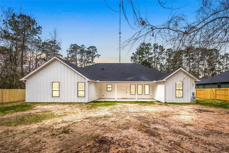 Spacious backyard with partial grass and mature trees, enclosed by a wooden fence, perfect for privacy and outdoor activities.