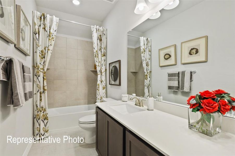 Bathroom featuring a bathtub with tiled surround, a built-in shelf, and a dark wood-finish vanity with a white countertop and integrated sink