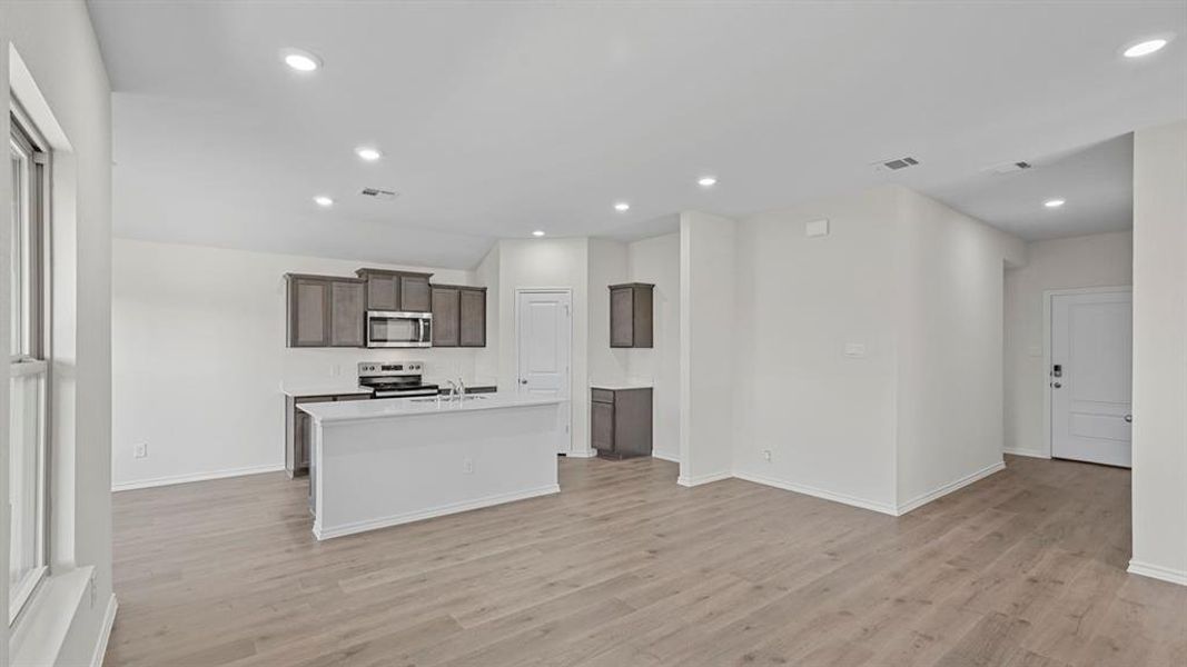 Kitchen featuring dark wood finish cabinets, stainless steel appliances, a kitchen island with sink, recessed lighting, and open floor plan