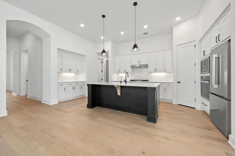 Kitchen with a kitchen breakfast bar, white cabinetry, arched walkways, appliances with stainless steel finishes, and backsplash