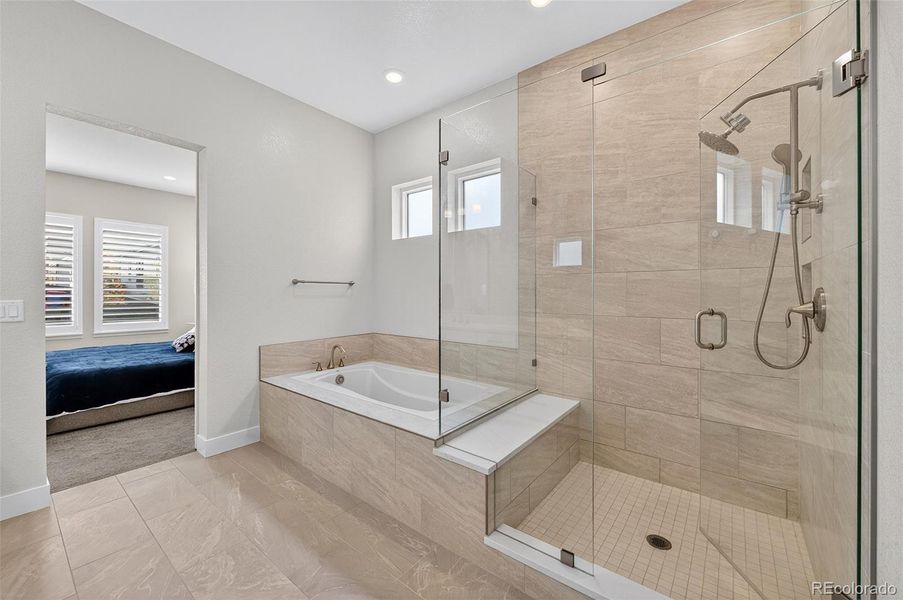 Primary Bathroom (Tub & Shower View) – Spa-inspired bath featuring a soaking tub, frameless glass shower, and sleek tile surround for a refined finish.