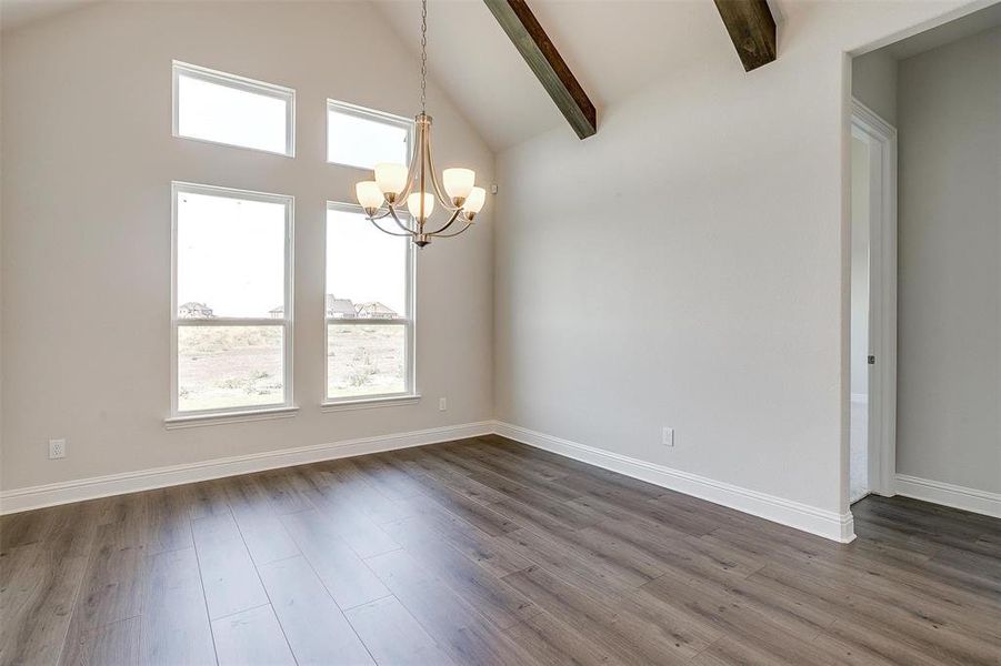 Unfurnished room featuring an inviting chandelier, beam ceiling, high vaulted ceiling, and dark wood-type flooring