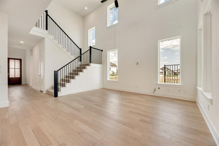 Entrance foyer featuring healthy amount of natural light, light wood-style flooring, stairway, a high ceiling, and recessed lighting Entrance foyer featuring healthy amount of natural light, light wood-style flooring, stairway, a high ceiling, and recessed lighting