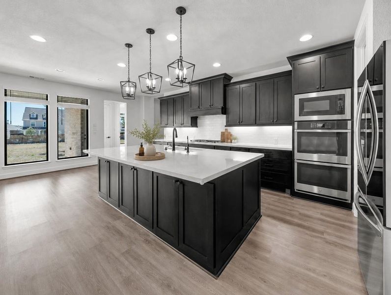 A well-appointed kitchen showcasing a spacious island with ample counter space and modern black cabinetry. A well-appointed kitchen showcasing a spacious island with ample counter space and modern black cabinetry.