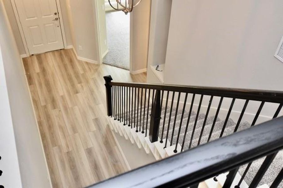 Staircase with wood finished floors and a chandelier