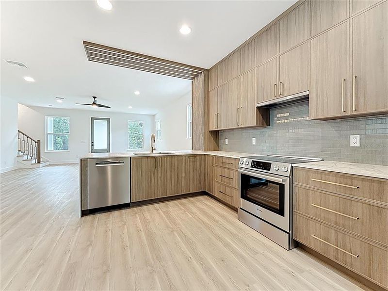 Sleek and modern kitchen featuring custom wood cabinetry, quartz waterfall countertops, stainless steel appliances, and stylish accent details — all bathed in natural light. Sleek and modern kitchen featuring custom wood cabinetry, quartz waterfall countertops, stainless steel appliances, and stylish accent details — all bathed in natural light.