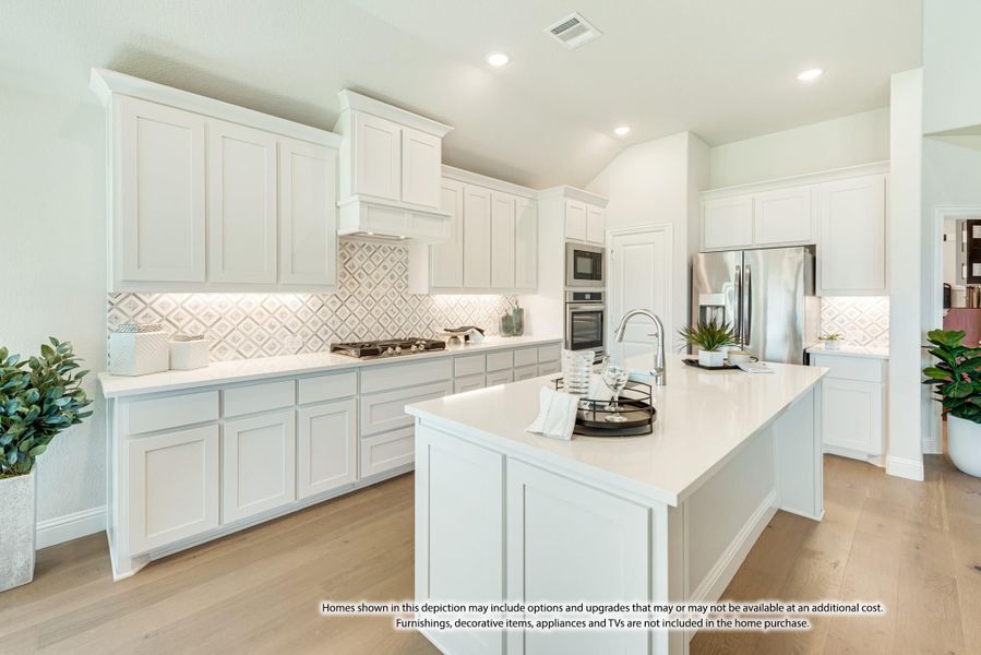 White kitchen with large center island, stainless steel appliances, patterned tile backsplash, and light wood floors White kitchen with large center island, stainless steel appliances, patterned tile backsplash, and light wood floors