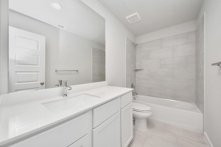 Secondary bath features tile flooring, bath/shower combo with tile surround, light stained wood cabinets, beautiful light countertop. Sample photo of completed home with similar floor plan. Actual colors and selections may vary. Secondary bath features tile flooring, bath/shower combo with tile surround, light stained wood cabinets, beautiful light countertop. Sample photo of completed home with similar floor plan. Actual colors and selections may vary.