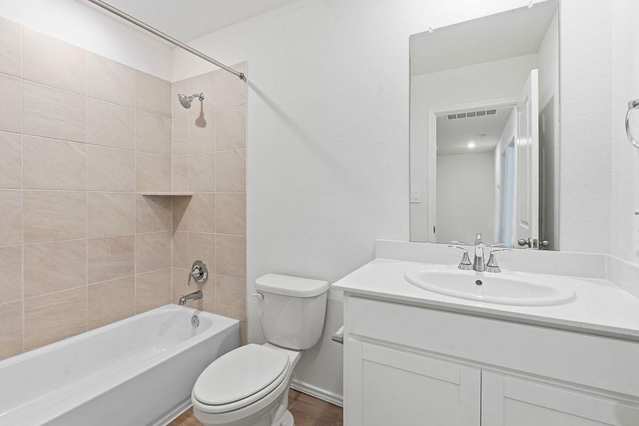 Full bathroom featuring a white vanity with an integrated sink, a rectangular mirror, and a toilet