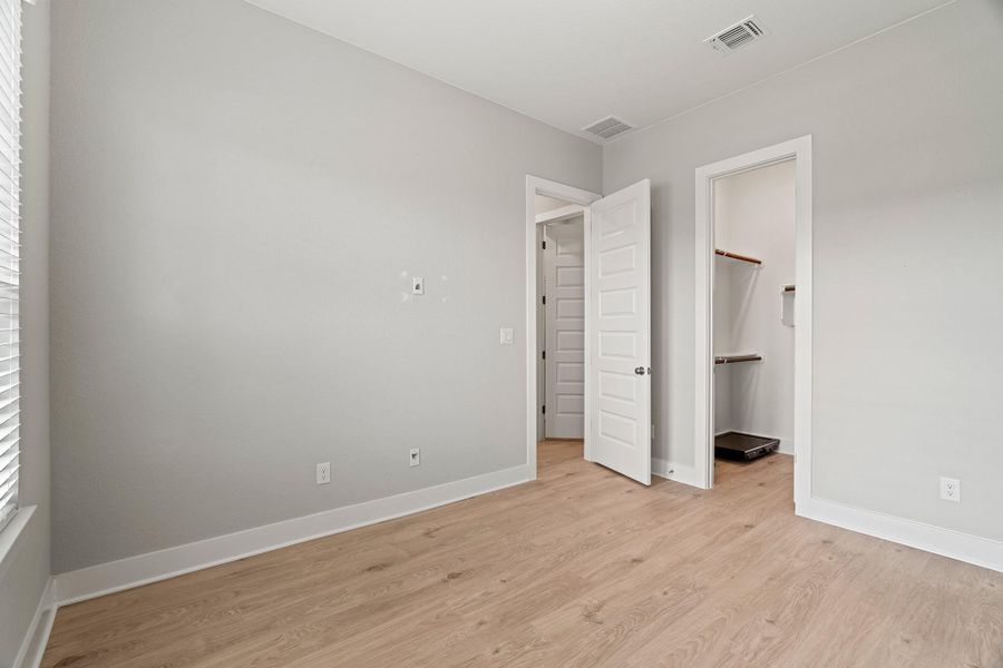 Unfurnished bedroom featuring light wood-type flooring, multiple windows, and a spacious closet Unfurnished bedroom featuring light wood-type flooring, multiple windows, and a spacious closet