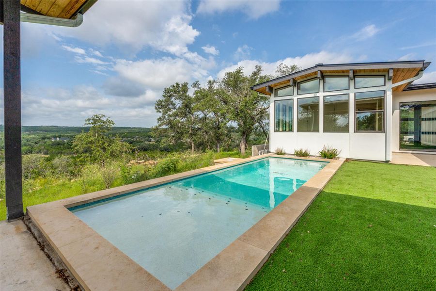 An inviting pool alongside a contemporary home offers a refreshing escape with panoramic landscape views.
