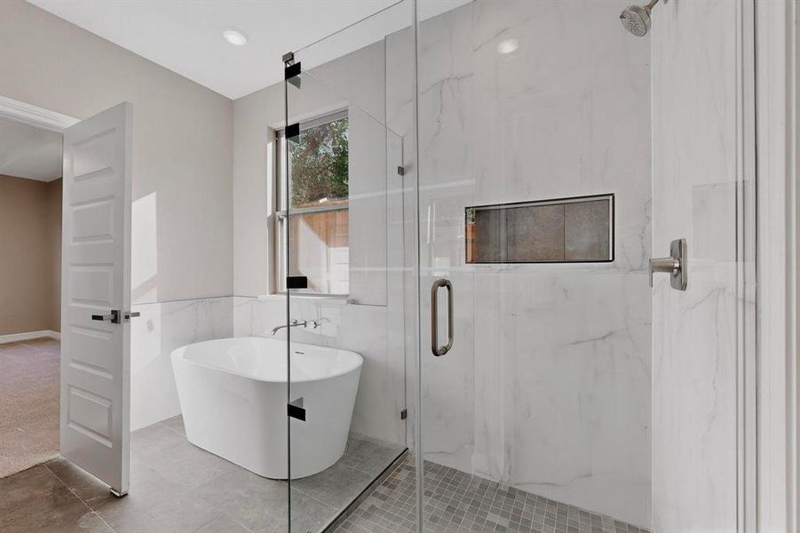 Bathroom with a freestanding tub, a marble finish shower, tile patterned flooring, and tile walls