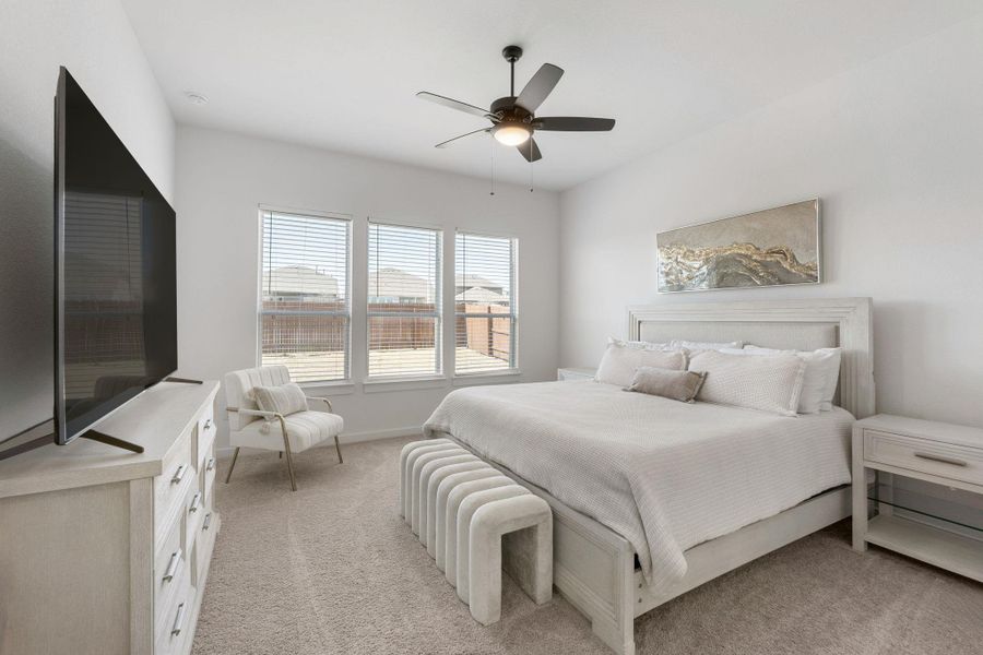 Main bedroom with light colored carpet, baseboards, and a ceiling fan