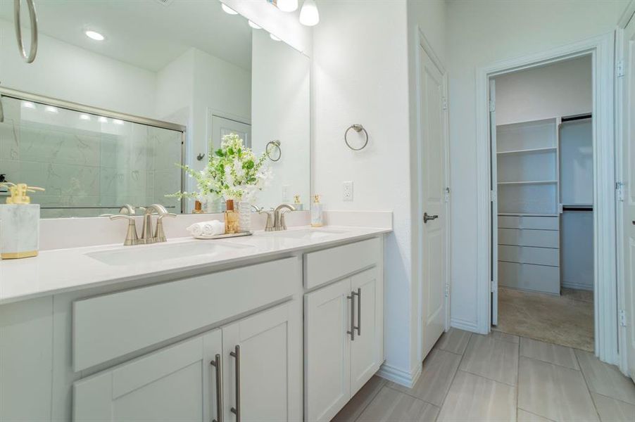Full bathroom featuring a stall shower, double vanity, and a walk in closet Full bathroom featuring a stall shower, double vanity, and a walk in closet