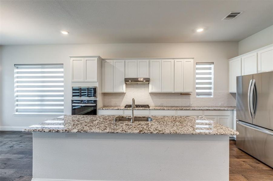 Kitchen featuring appliances with stainless steel finishes, a sink, white cabinets, backsplash, and dark wood-style floors
