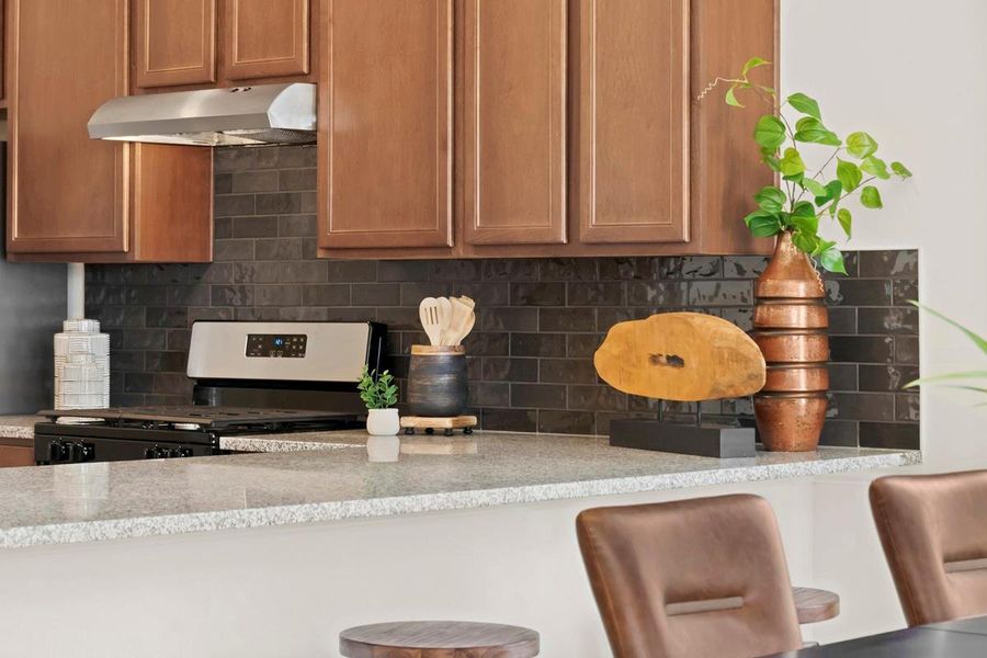 An elegant breakfast bar extends the dining area, providing a casual and inviting spot for morning meals, additional seating for guests, or a seamless workspace in the heart of the home.