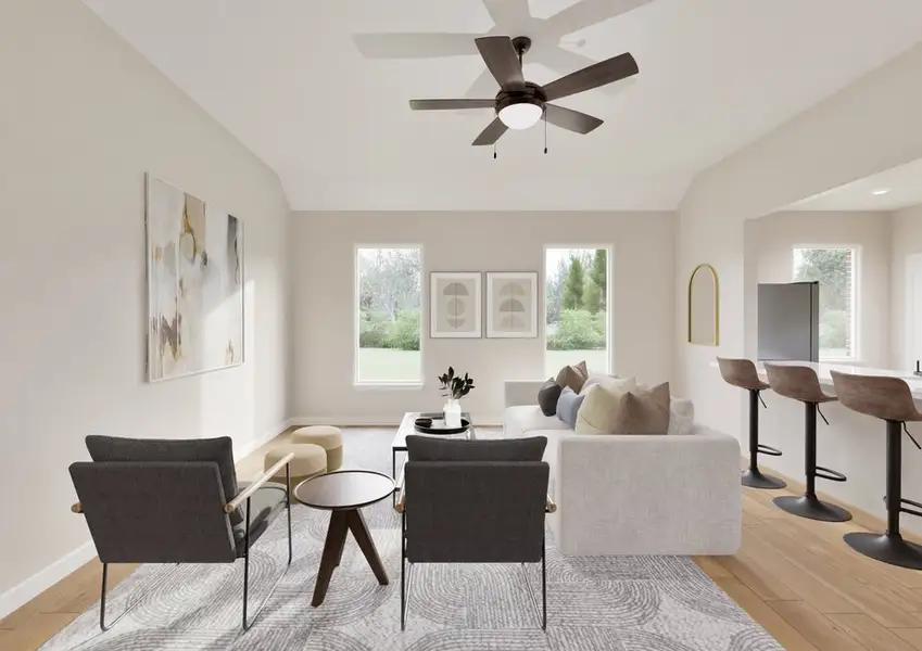 Modern living room with neutral tones, featuring gray armchairs, a light couch, and abstract art. Large windows and a breakfast bar add brightness.