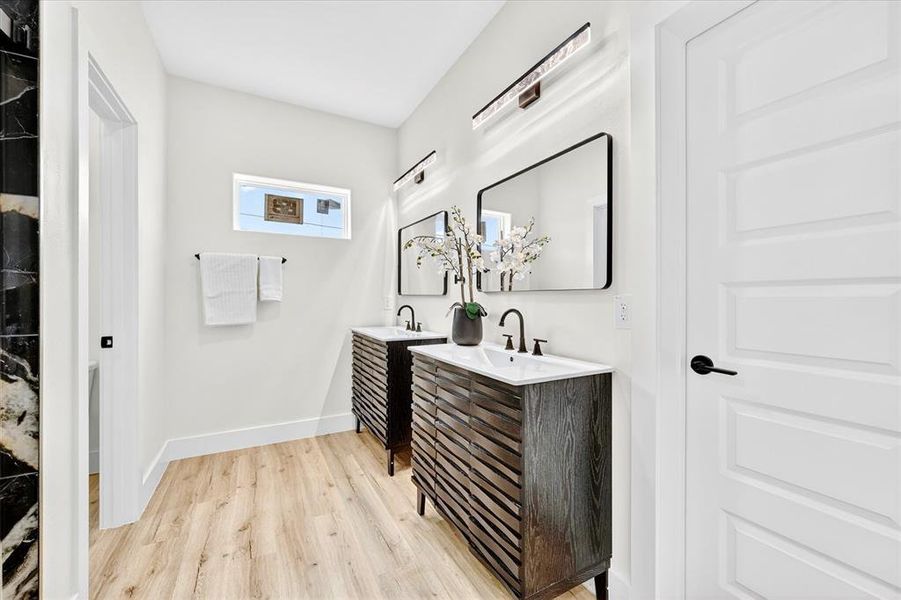 Bathroom featuring dual vanities with dark wood-finish cabinetry, rectangular vessel sinks, and matte black fixtures