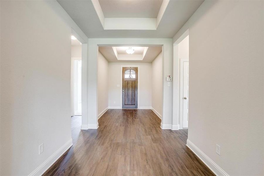 Corridor featuring a tray ceiling and dark hardwood / wood-style floors