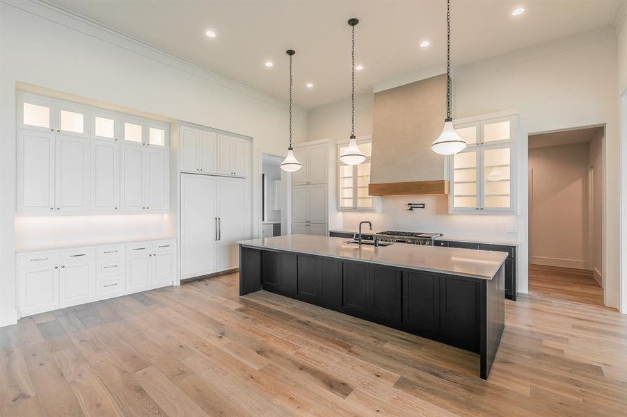 Kitchen featuring glass insert cabinets, dark cabinets, decorative light fixtures, a large island, and recessed lighting