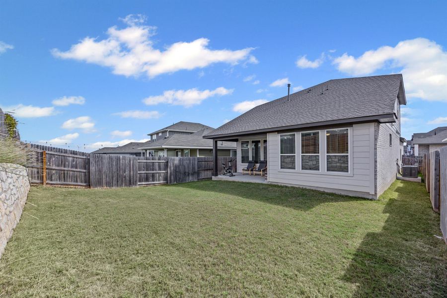 Rear view of house featuring a patio, a shingled roof, and a fenced backyard
