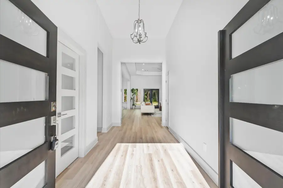 This photo showcases a bright, welcoming entryway with modern double doors, light wood flooring, and high ceilings. The open layout leads to a spacious living area with natural light streaming in, creating an inviting atmosphere. This photo showcases a bright, welcoming entryway with modern double doors, light wood flooring, and high ceilings. The open layout leads to a spacious living area with natural light streaming in, creating an inviting atmosphere.