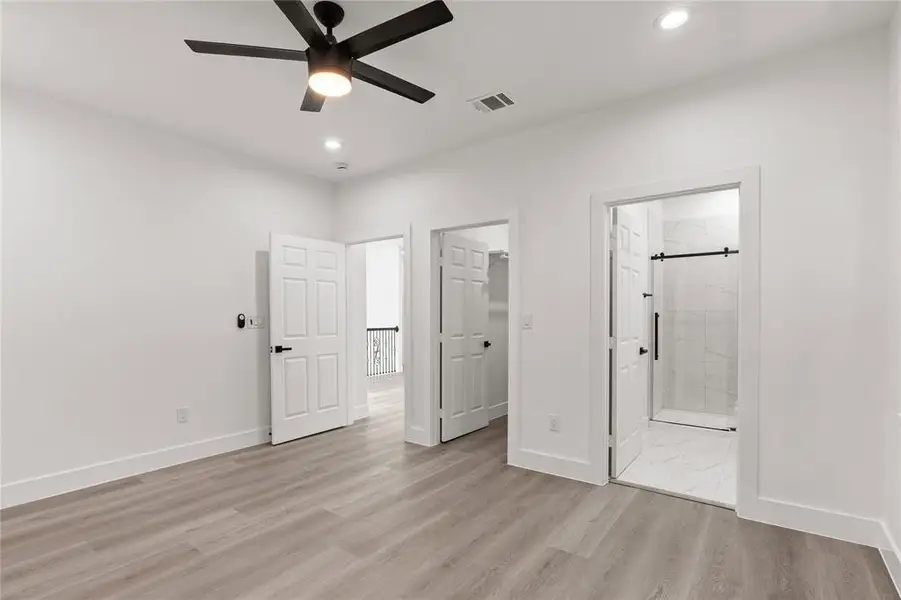 Unfurnished bedroom with light wood-type flooring, connected bathroom, recessed lighting, a walk in closet, and ceiling fan