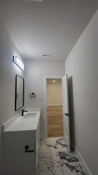 Bathroom with visible vents, baseboards, vanity, and marble finish floor
