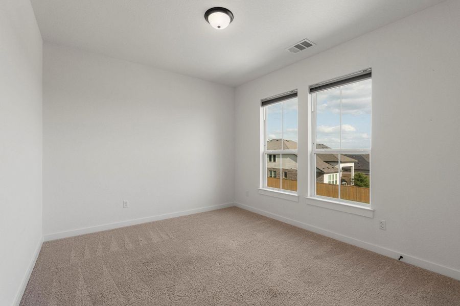 A well-proportioned bedroom offers carpeted flooring and ample natural light from two large windows.