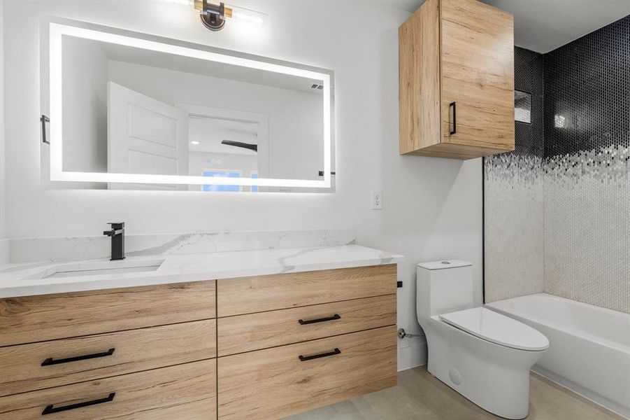 Bathroom featuring shower / bathing tub combination, toilet, and vanity