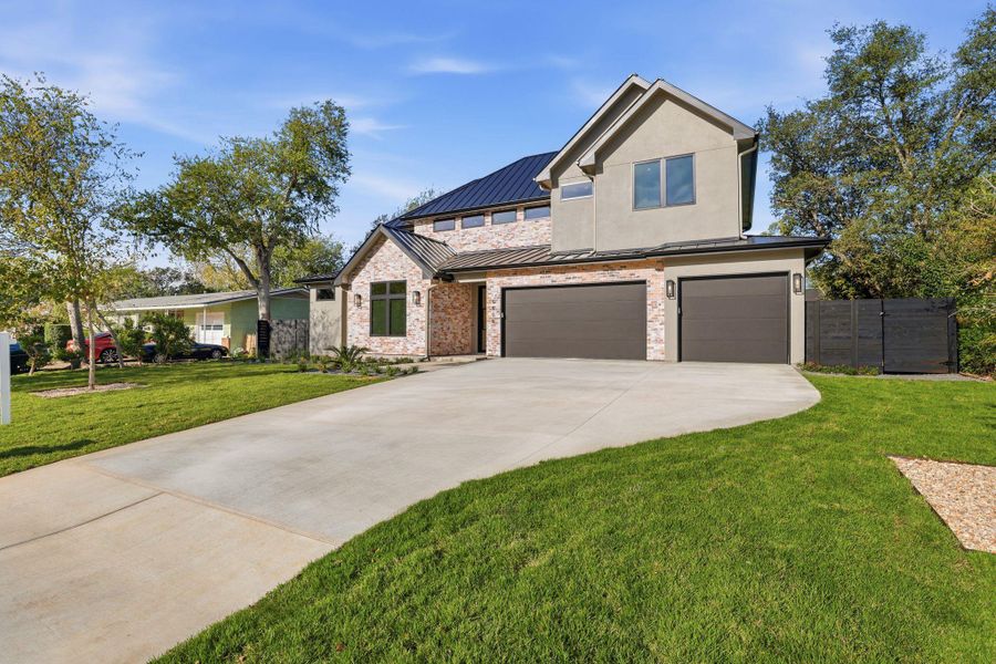 View of front of home with a standing seam roof, a metal roof, driveway, an attached garage, and stucco siding View of front of home with a standing seam roof, a metal roof, driveway, an attached garage, and stucco siding