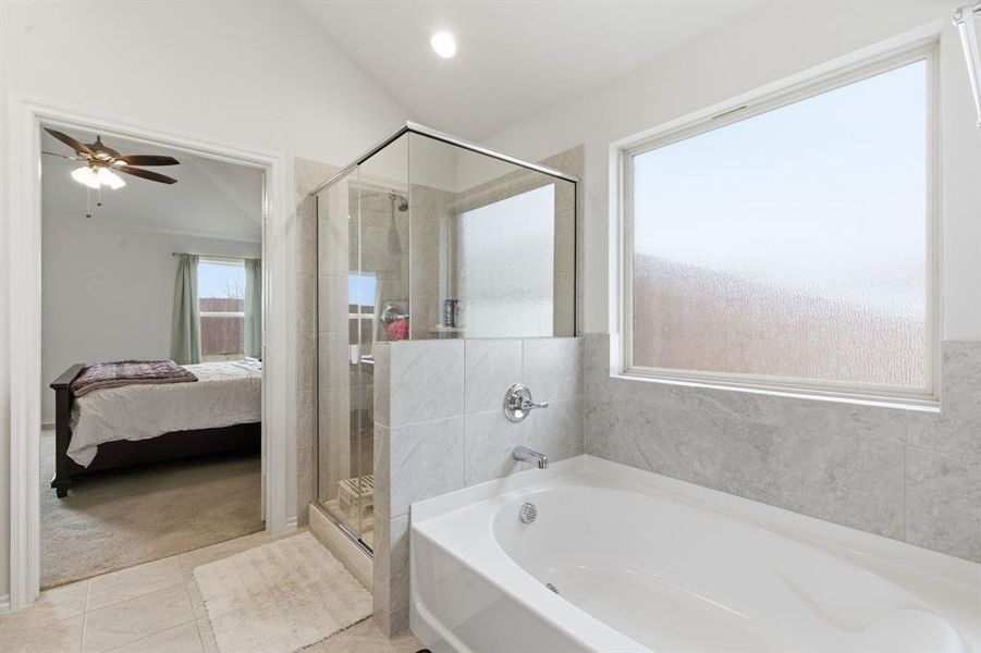 Ensuite bathroom featuring lofted ceiling, a stall shower, a garden tub, light carpet, and ceiling fan
