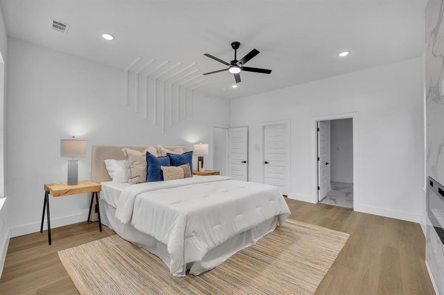 Bedroom with connected bathroom, light hardwood / wood-style floors, and ceiling fan