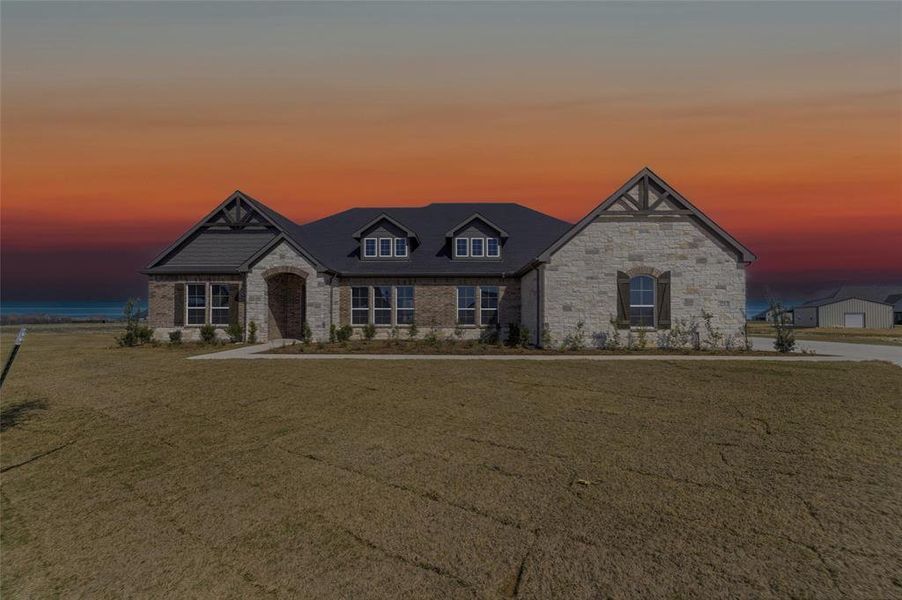 French country inspired facade featuring stone siding and a front yard French country inspired facade featuring stone siding and a front yard