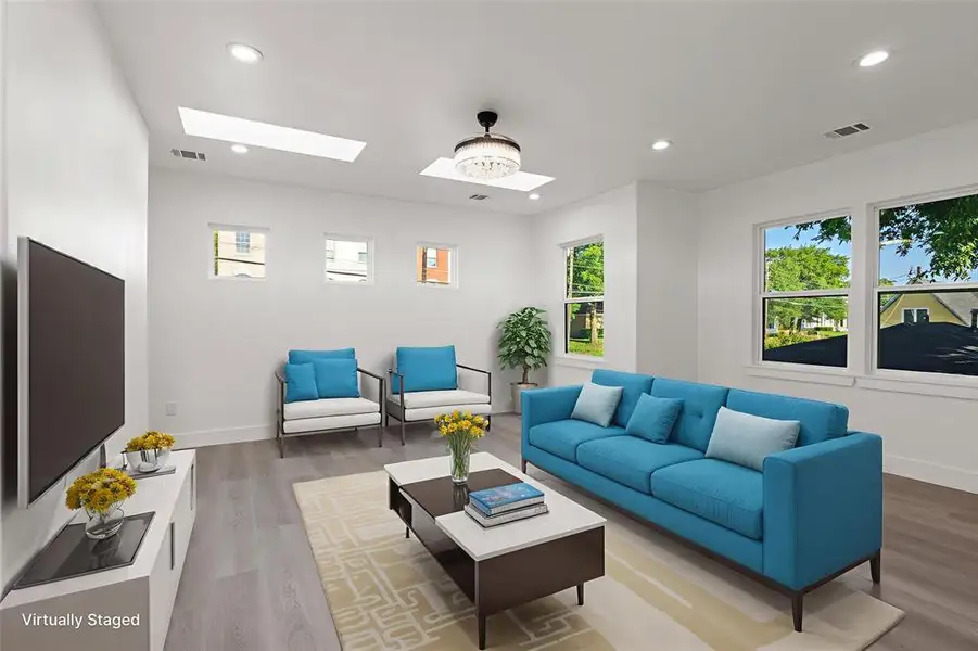 Living area featuring recessed lighting, wood finished floors, plenty of natural light, and a skylight