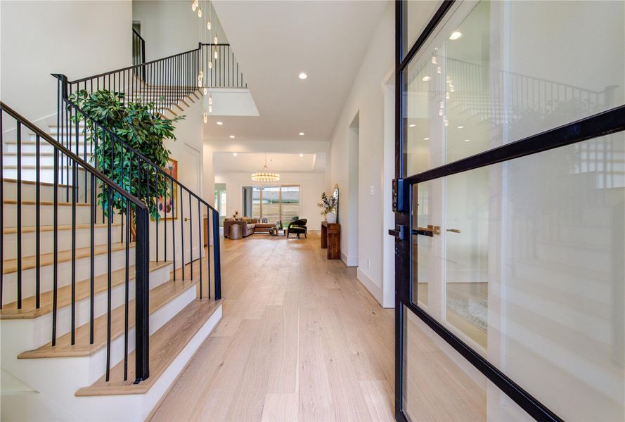 A dramatic entry welcomes guests with soaring ceilings, wide-plank hardwood floors, a statement staircase, and an immediate sense of scale and elegance.