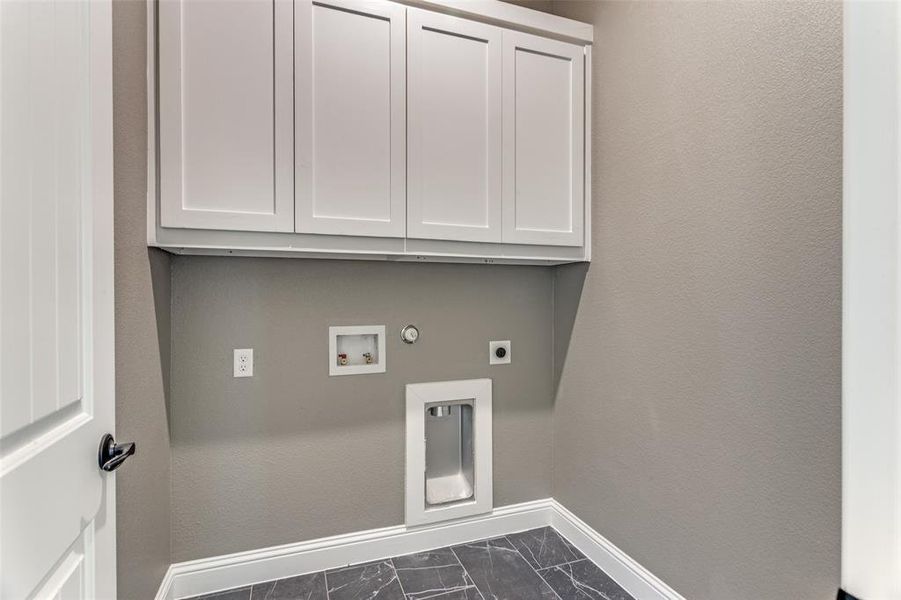 Laundry room featuring hookup for an electric dryer, cabinet space, washer hookup, hookup for a gas dryer, and dark marble finish flooring Laundry room featuring hookup for an electric dryer, cabinet space, washer hookup, hookup for a gas dryer, and dark marble finish flooring