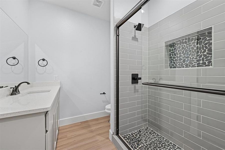 Bathroom featuring vanity, toilet, an enclosed shower, and wood-type flooring